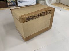 A re-used box with previous handwriting and corporate logos on it covered up with kraft paper tape to look like a clean box