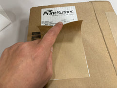 Covering up a shipping label on a box with a kraft paper label blocker sticker