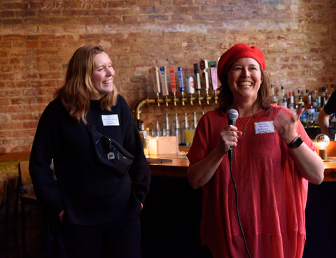 Valerie from Walnut Studiolo Wearing a Red Beret and Holding a Microphone Giving a Speech While Smiling and Fellow Artisans Cooperative Board Member Olga Prushinskaya Looks On at the Start.coop Accelerator Launch