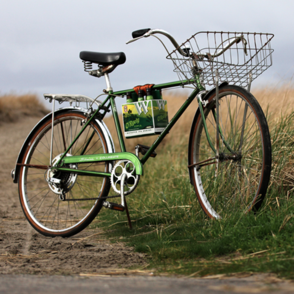 Green bike with 6-pack frame cinch used to hold cardboard beer carton.