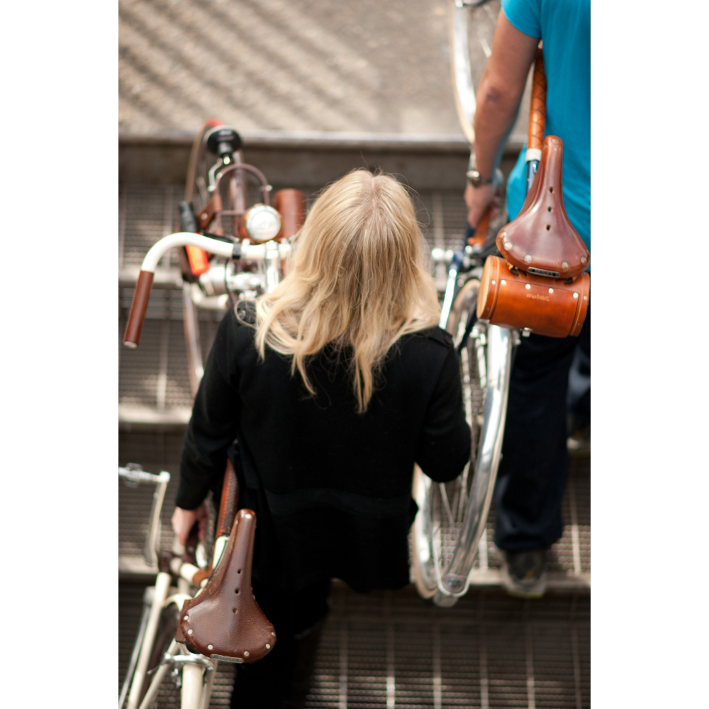 Birdseye view of two people walking up a set of stairs while carrying bikes with the &quot;little lifter&quot; handle