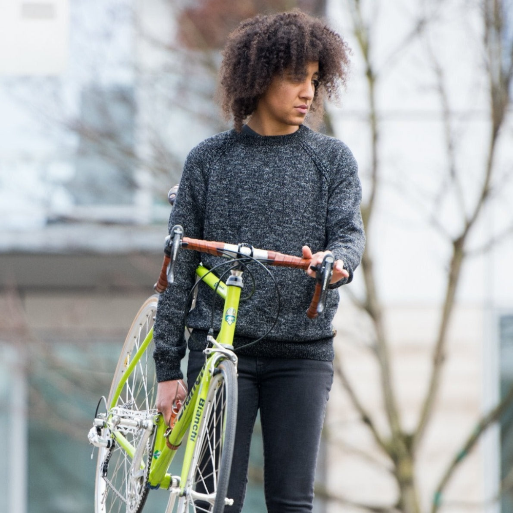 Front-on view of a lime green bicycle being carried by an African-American woman in a rain jacket using a Bicycle Frame Handle and the handlebars, which are wrapped in Dark Brown leather bar tape. 