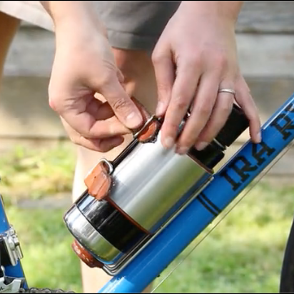 Person latching water bottle into the upcycle cage mounted drink holder