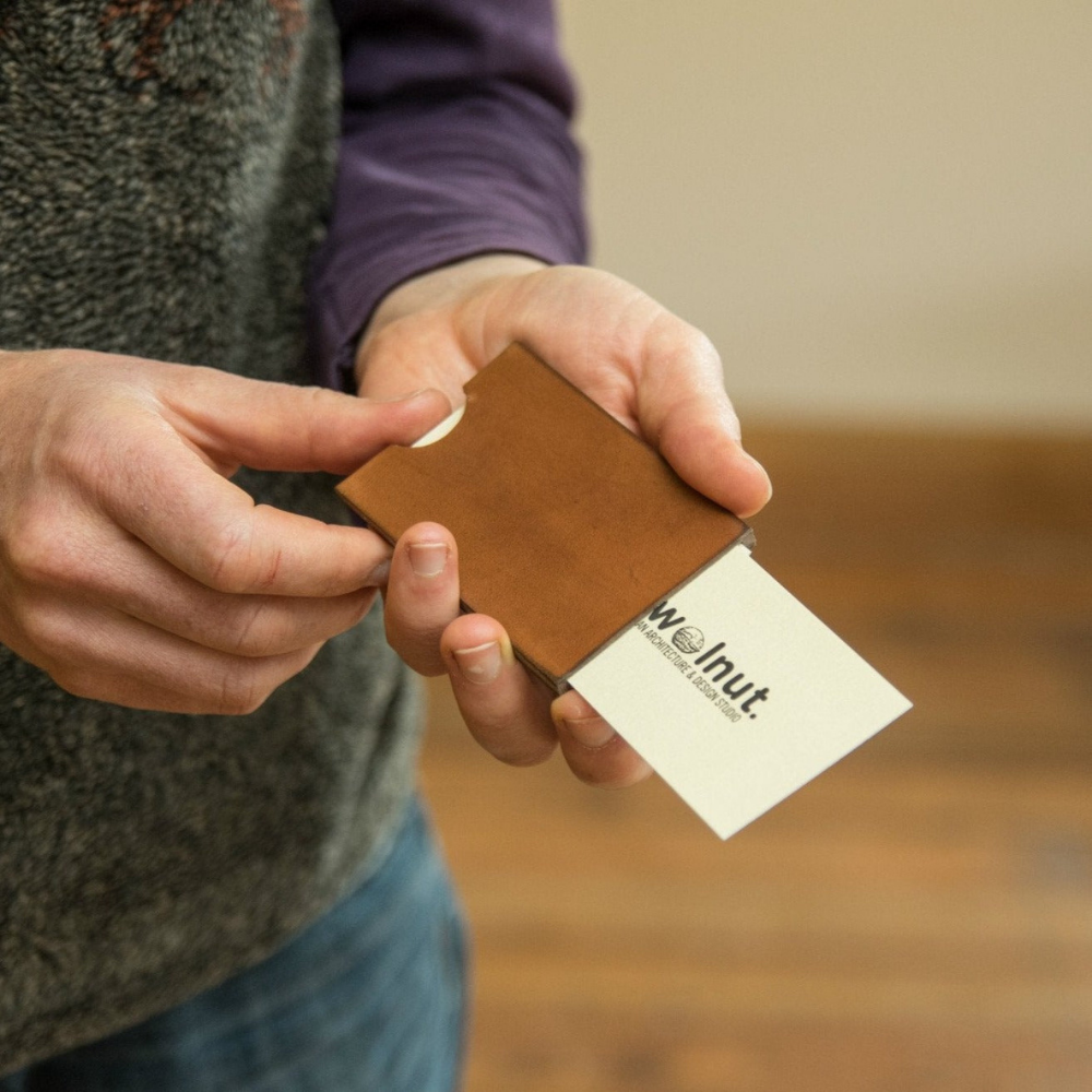 oman demonstrating how to push cards out of leather business card wallet