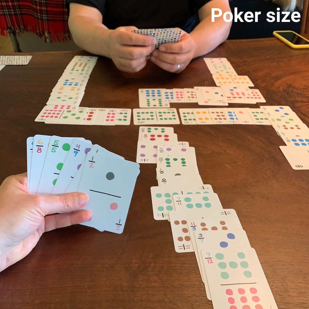 Travel dominoes in the larger poker size on a table with two people playing